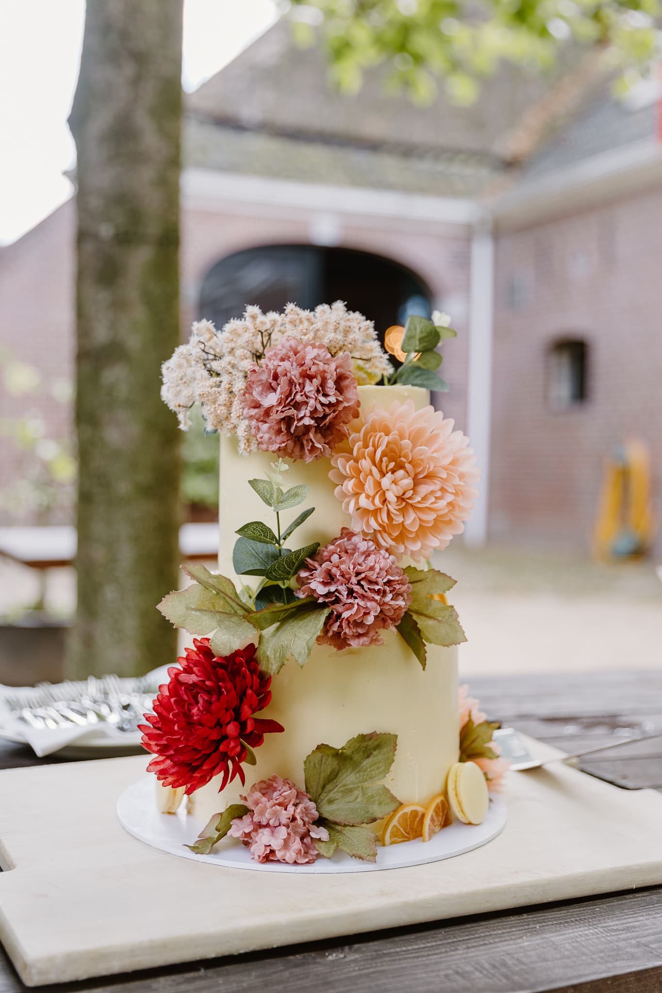 De bruidstaart bekleed met gekleurde bloemen buiten op een tafel in Drenthe.