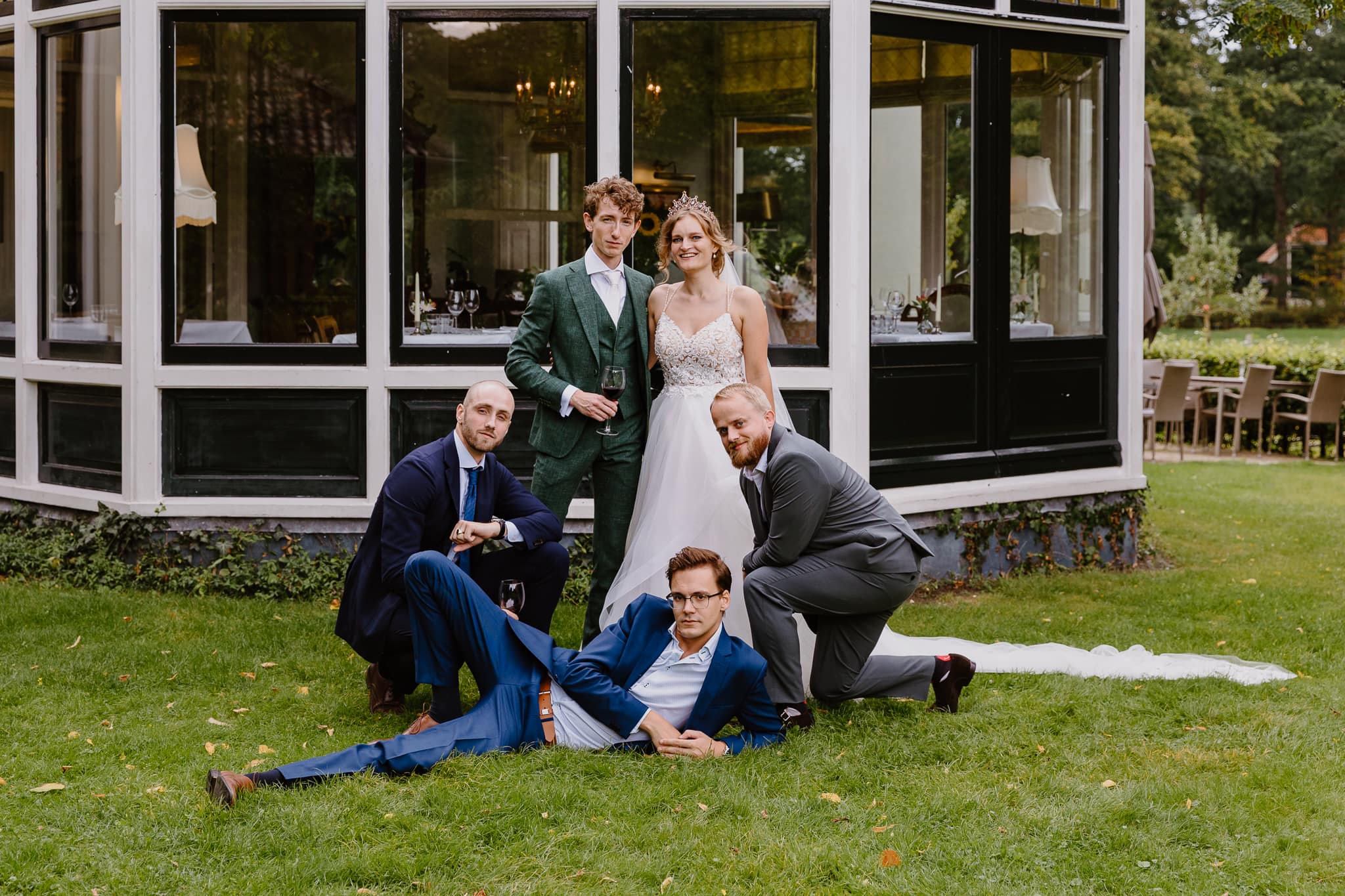 Bruidspaar met hun vriendengroep op het gras voor de Jufferen Lunsingh in Drenthe.