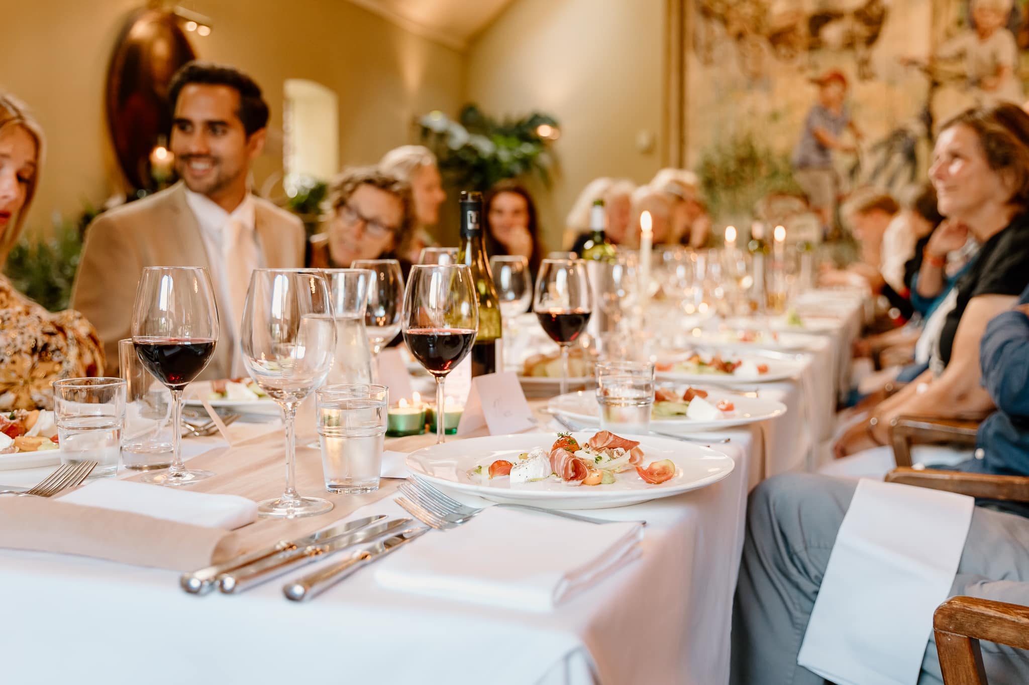 Mooi gedekte tafel met rode wijn en een voorgerecht met ham tijdens het diner van een bruiloft bij de Jufferen Lunsingh in Drenthe.