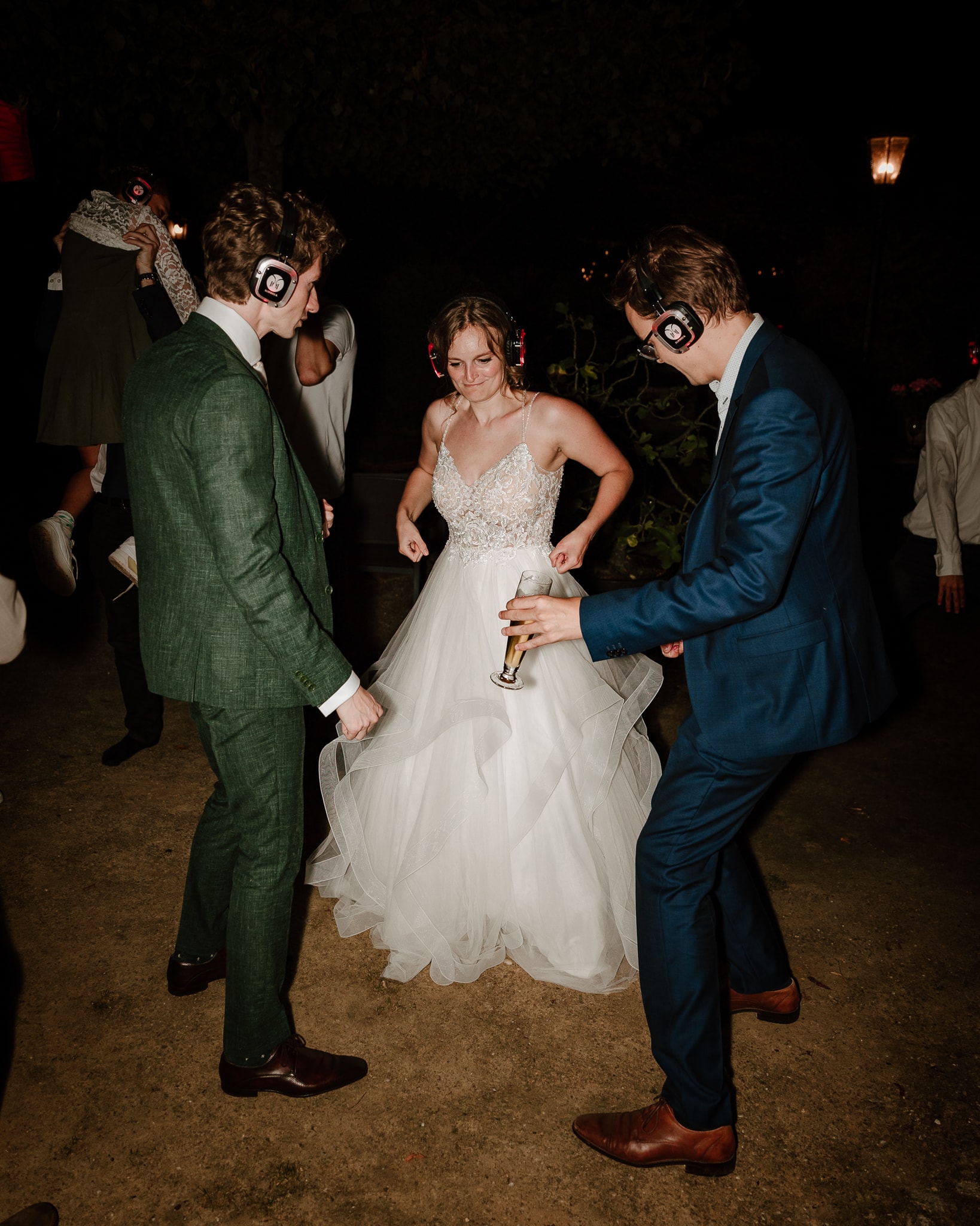 Bruidspaar danst met een vriend tijdens de silent disco op hun trouwfeest in Drenthe.