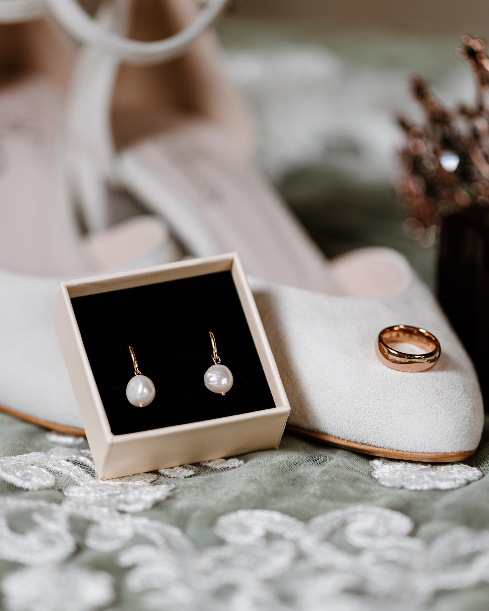 Fine art stijl trouwfotografie foto van de oorbellen, ring en trouwschoenen van de bruid.