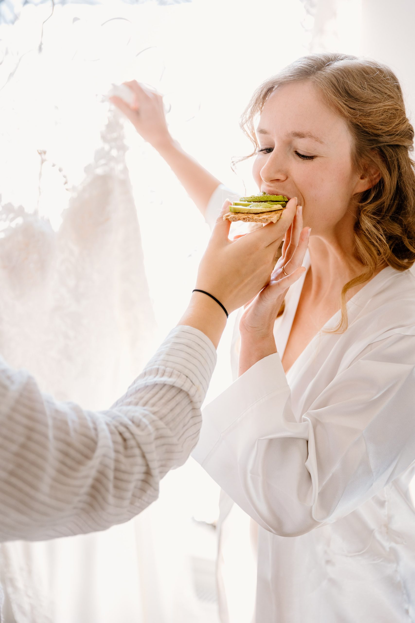 Een vrouw wordt voordat ze haar trouwjurk aantrekt wat eten gevoerd door haar zusje.