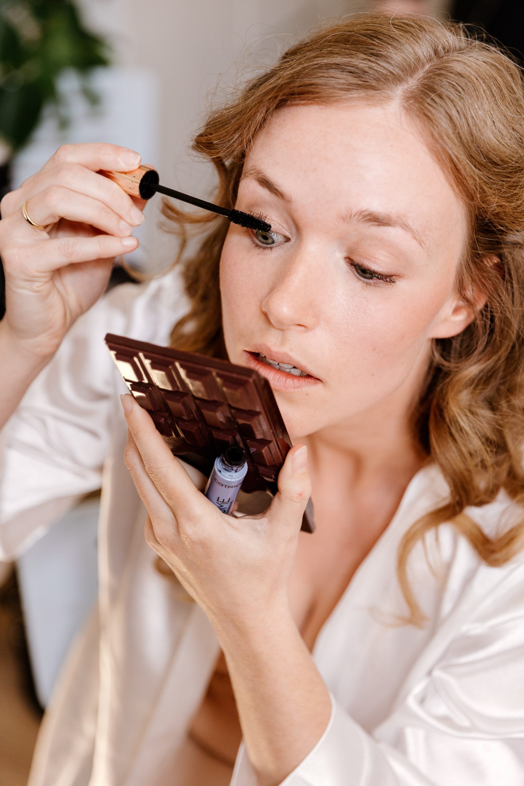 Een jonge vrouw doet haar eigen mascara op op haar trouwdag.