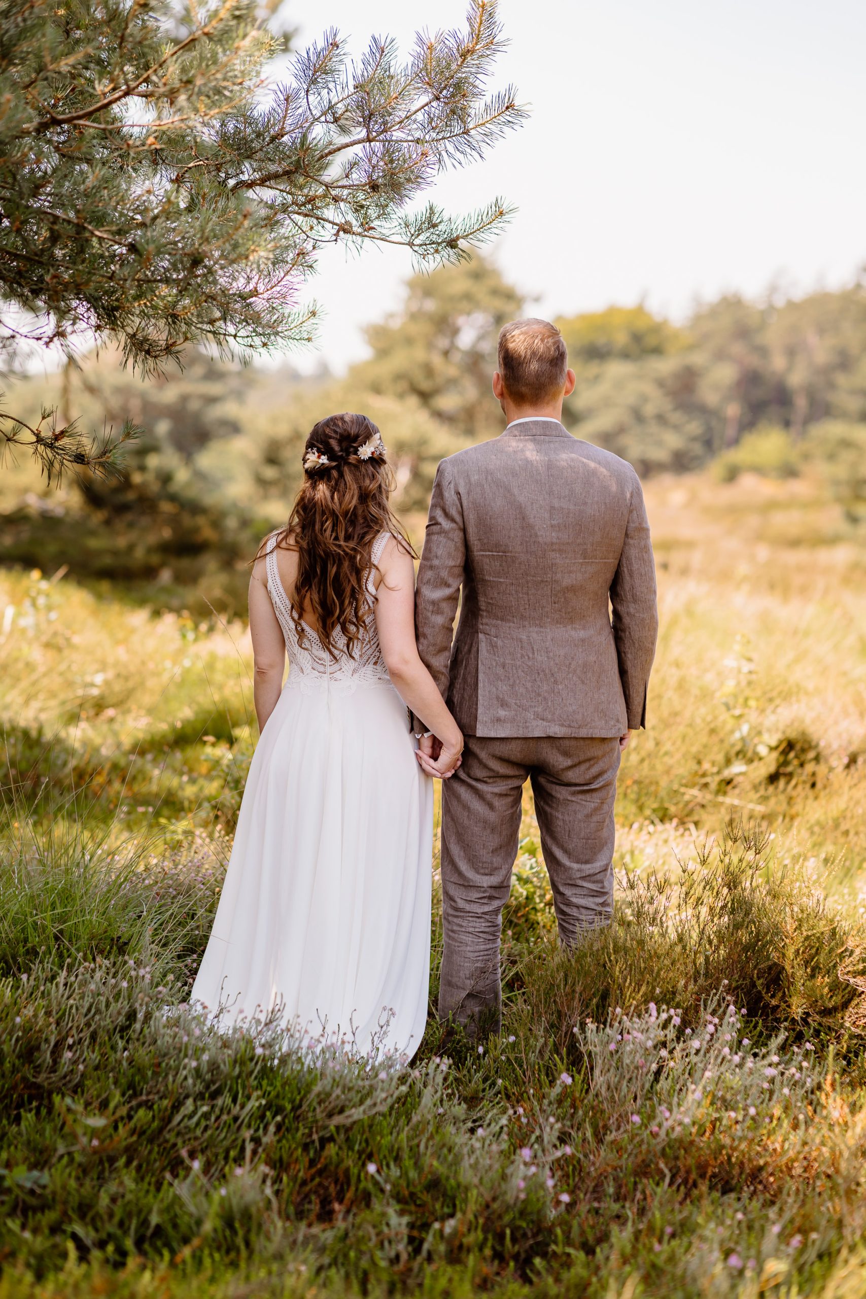 Een bruid en bruidegom, gefotografeerd door een trouwfotograaf uit Drenthe, staan in een grasveld.