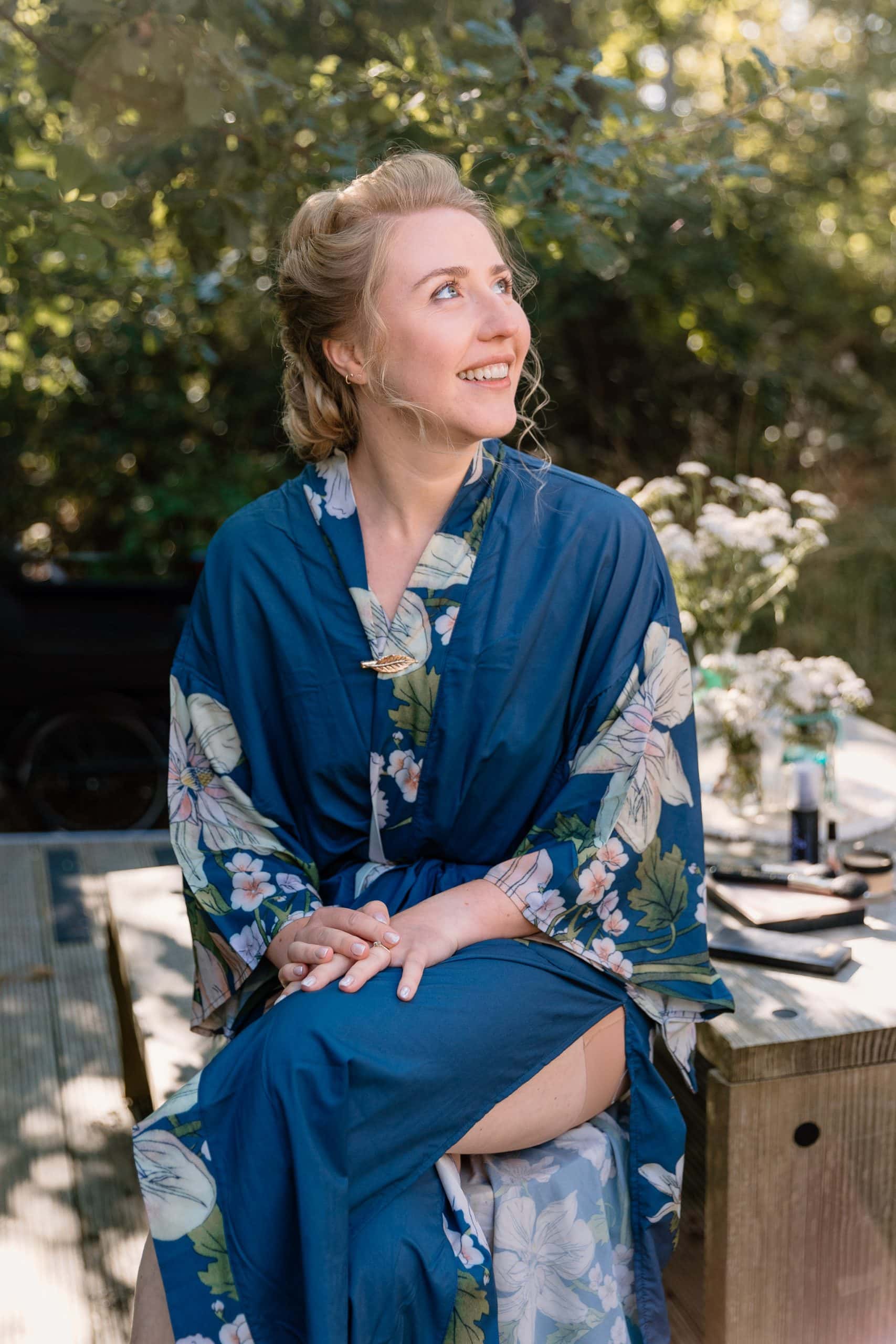 Een vrouw in een blauw gewaad zittend op een houten bankje bij Trouwen op Vlieland.