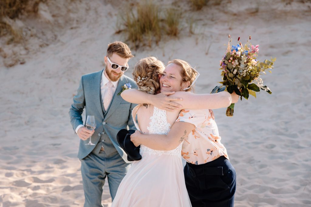 Een bruid en bruidegom knuffelen tijdens hun strandhuwelijk op Vlieland.