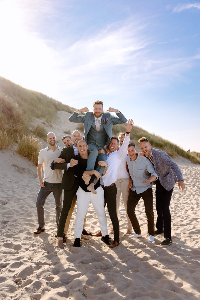 Een groep bruidsjonkers poseert voor een foto op het strand van Vlieland.