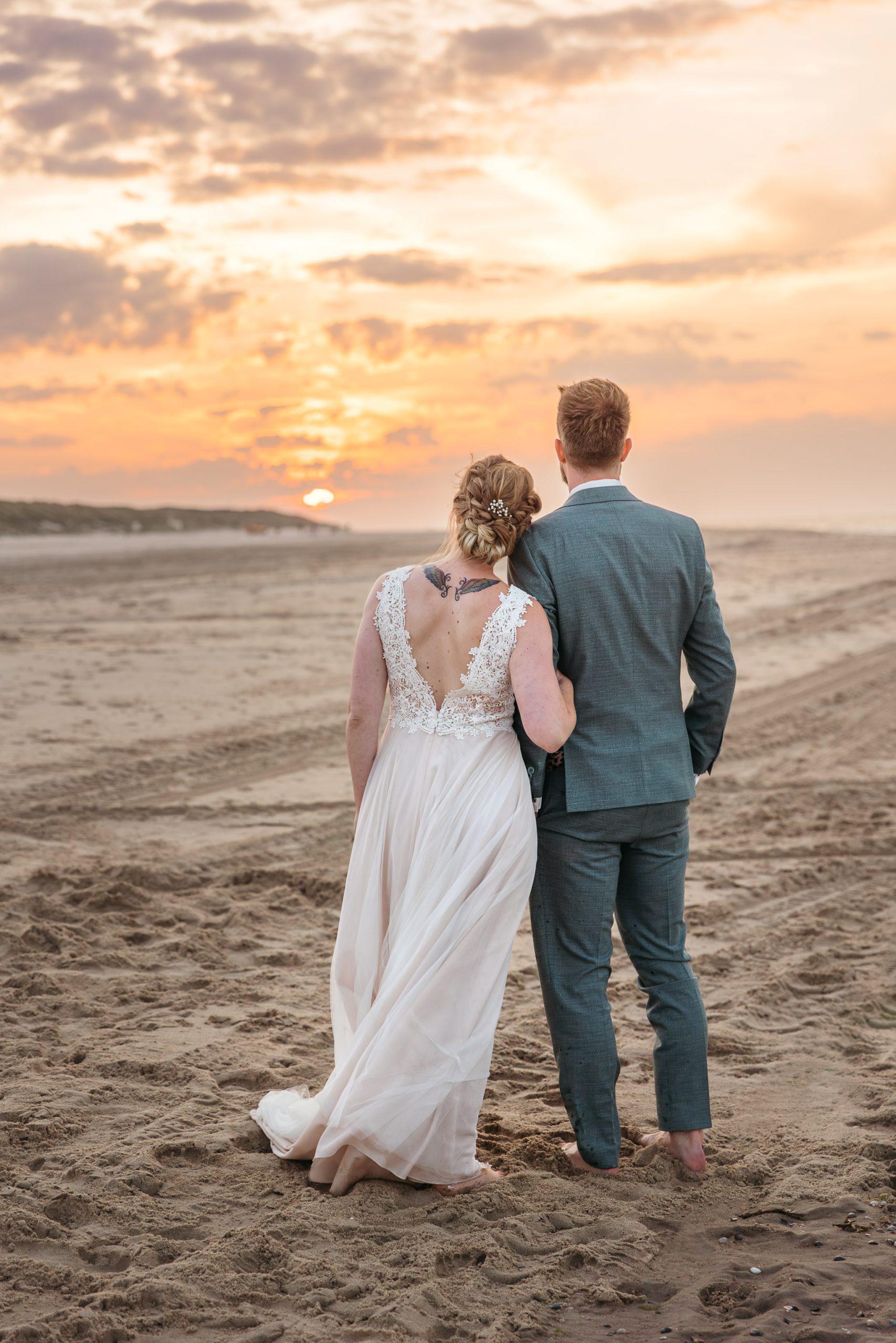 Een bruid en bruidegom trouwen op het strand bij zonsondergang op Vlieland.