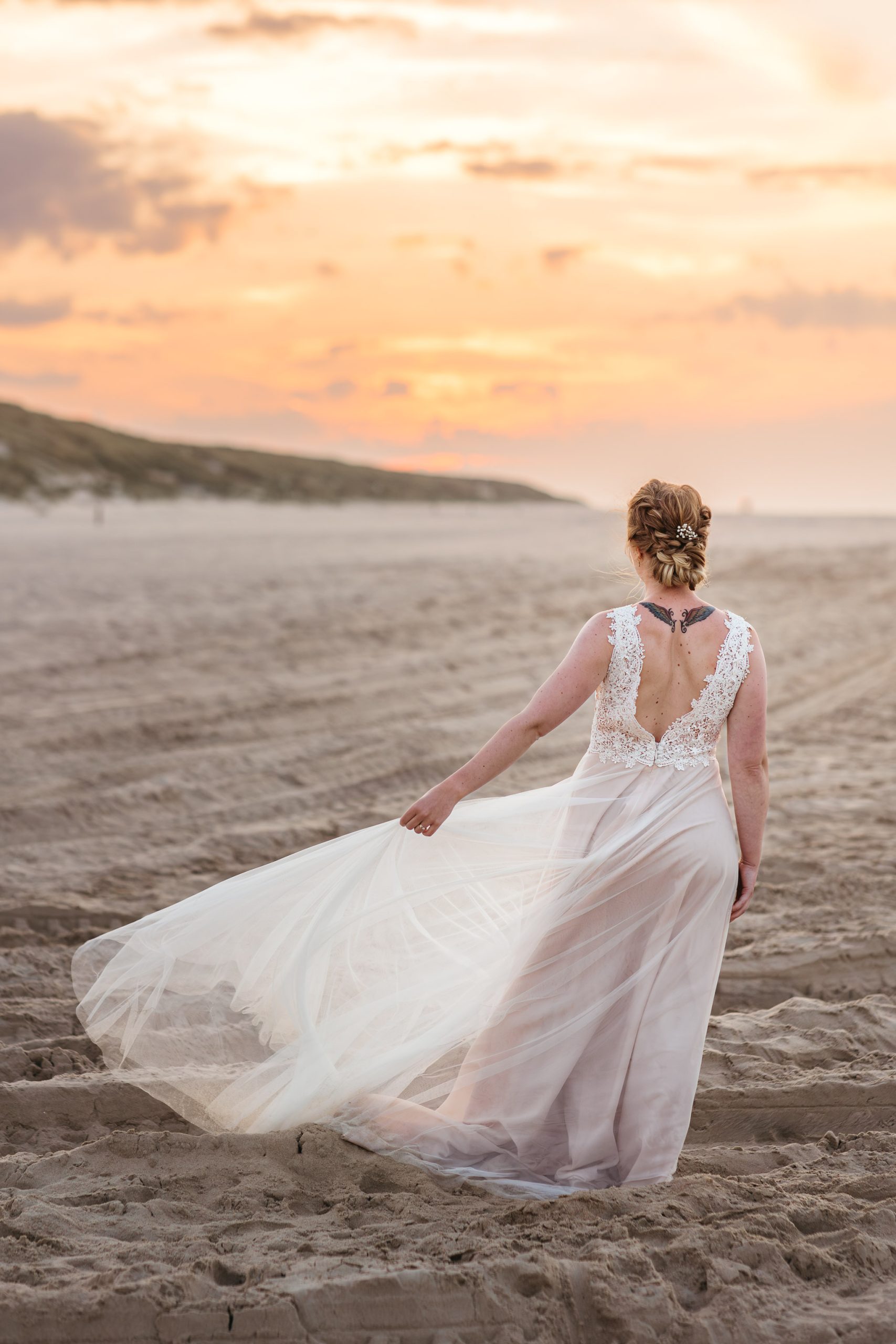 Een bruid in trouwjurk die bij zonsondergang over het strand loopt tijdens haar strandbruiloft op Vlieland.