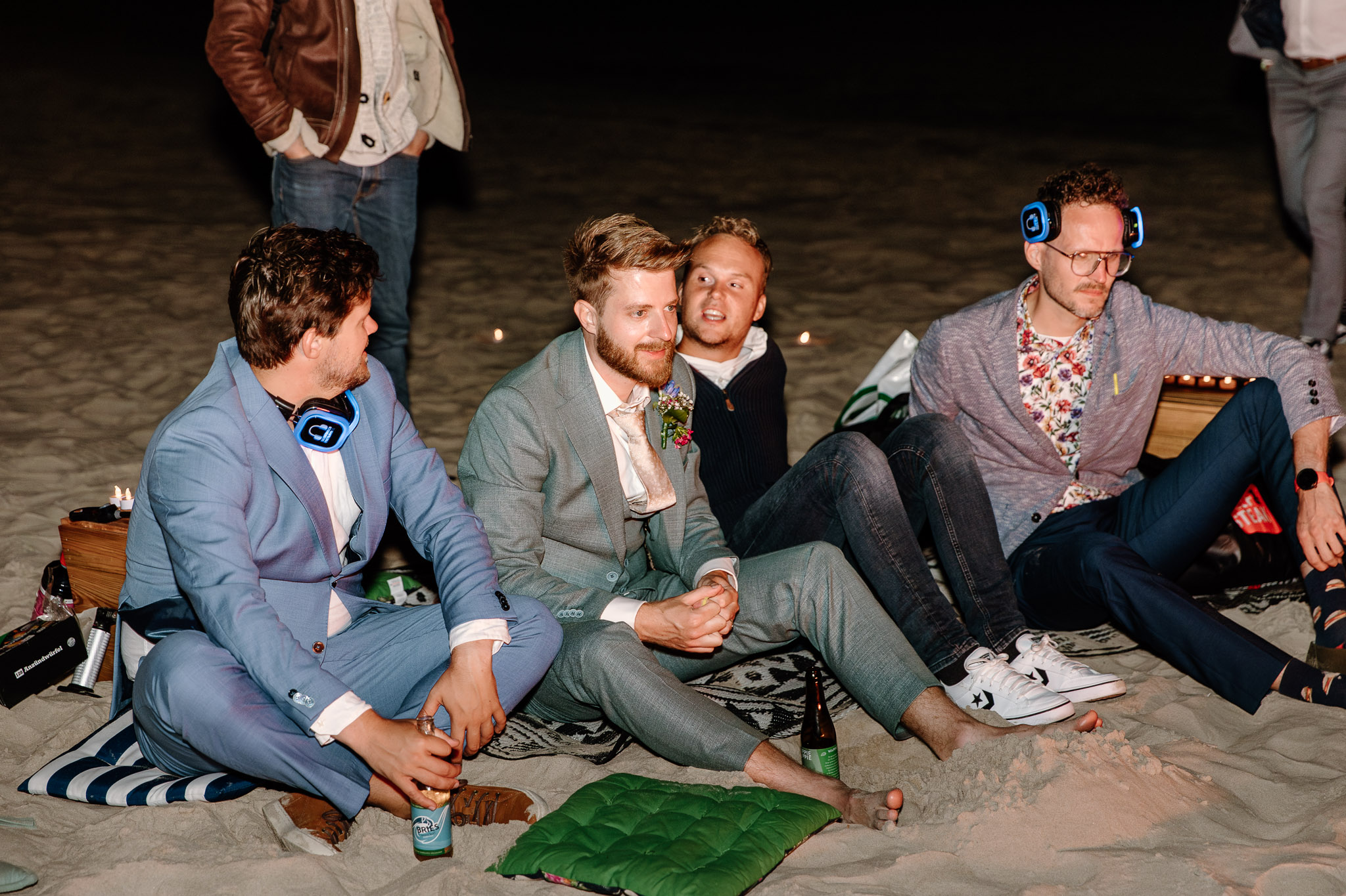 Een groep mannen zit op het strand van Vlieland, mogelijk voor een strandbruiloft.