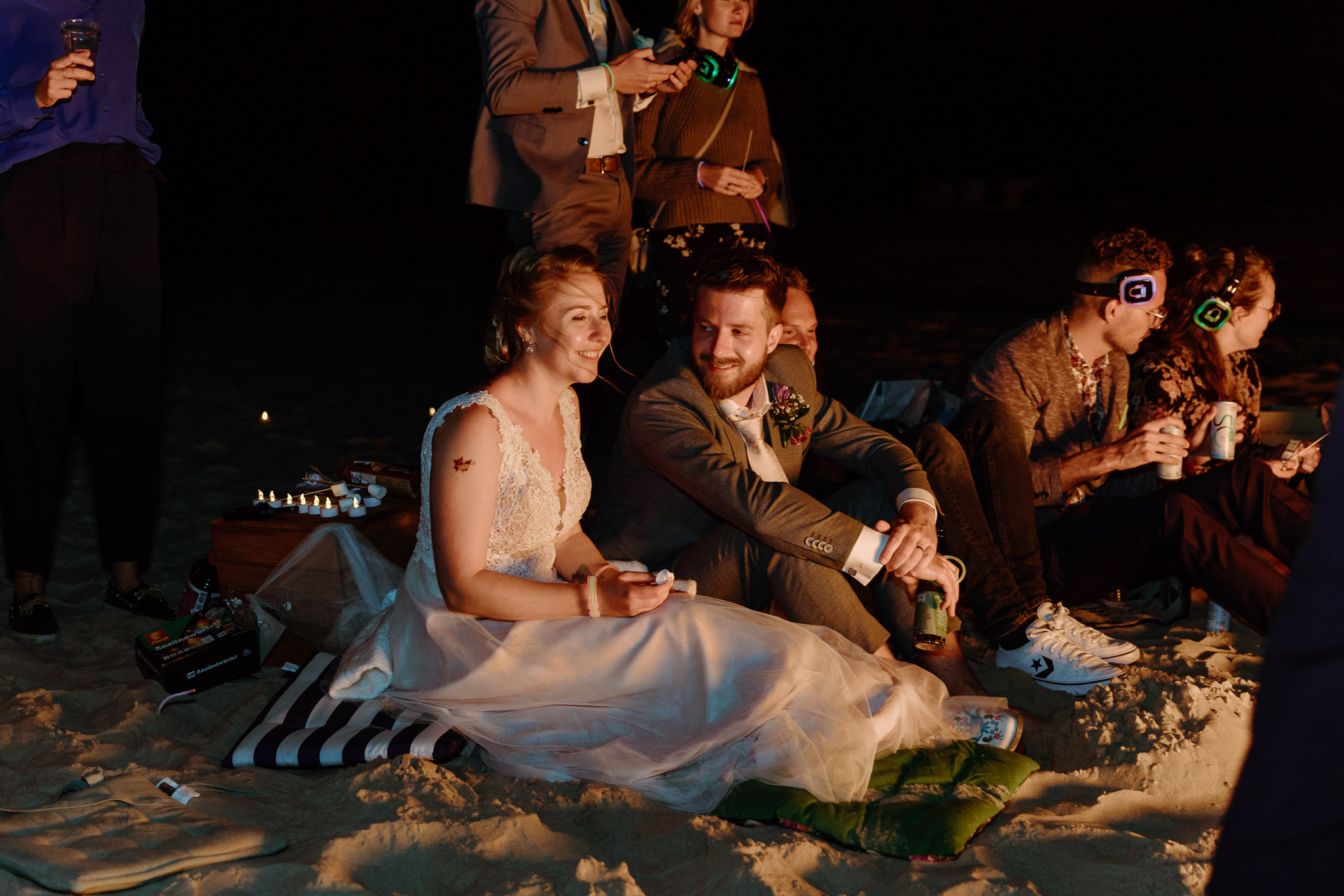 Een groep mensen zit 's nachts op het zand en geniet van een strandhuwelijksceremonie op Vlieland.