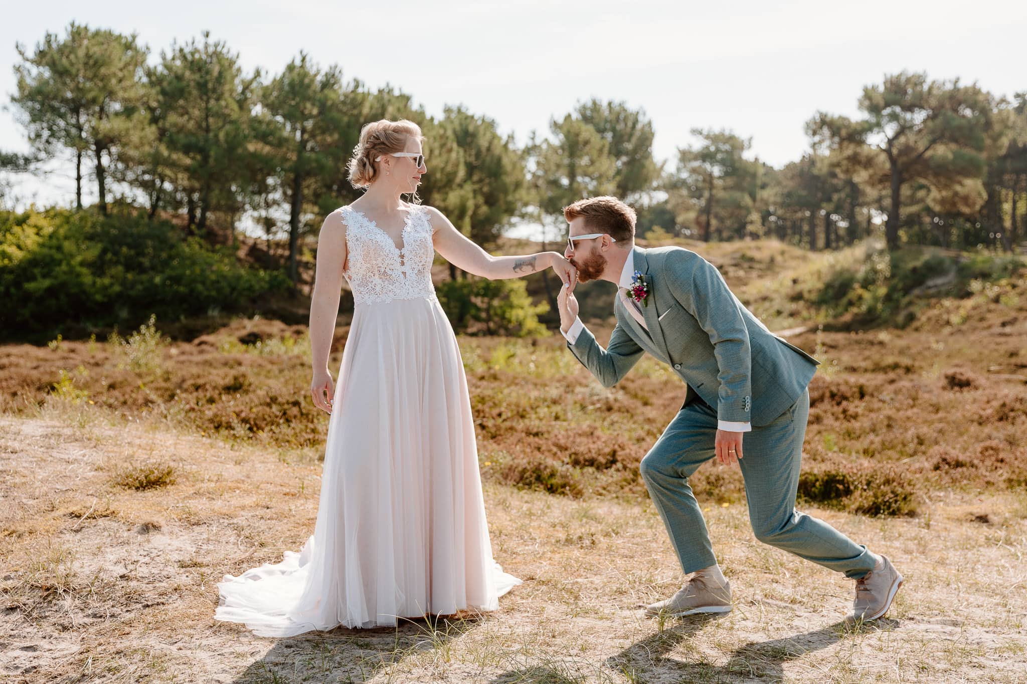 Trouwen op Vlieland - Een bruid en bruidegom die een romantische kus delen in een schilderachtig veld op hun speciale dag.