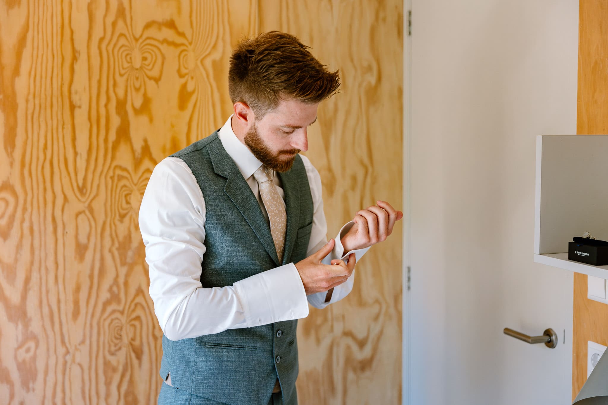 Een man in pak en stropdas, die angstig op zijn horloge kijkt terwijl hij wacht op de ceremonie in Trouwen op Vlieland.