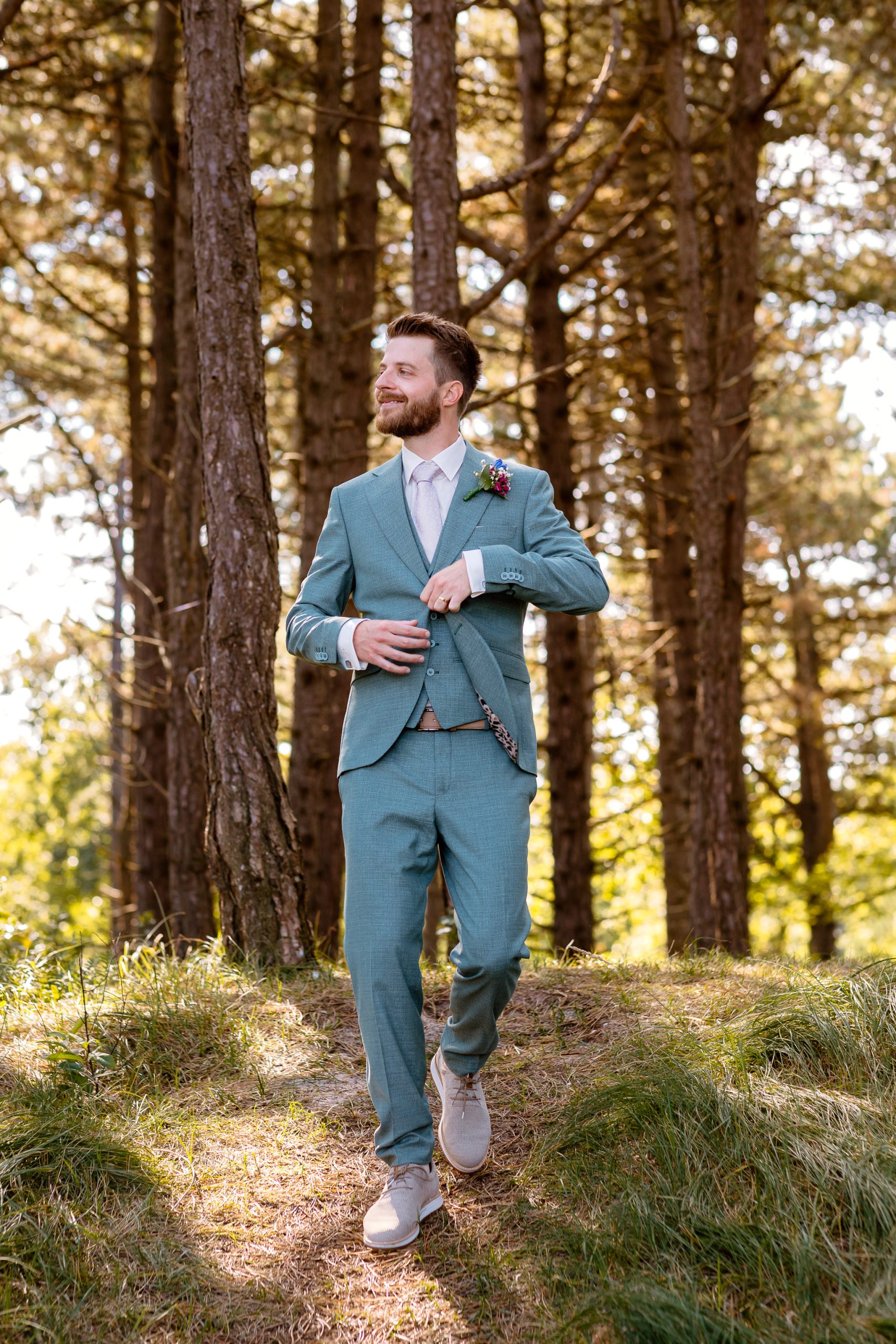 Een man in een blauw pak loopt door het bos op Vlieland.