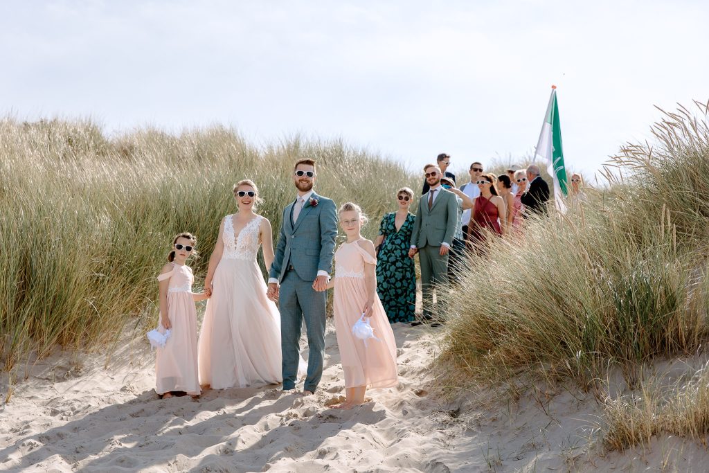 Een strandbruiloftfeestje dat sierlijk langs een zandduin loopt, ter ere van hun huwelijk op Vlieland.