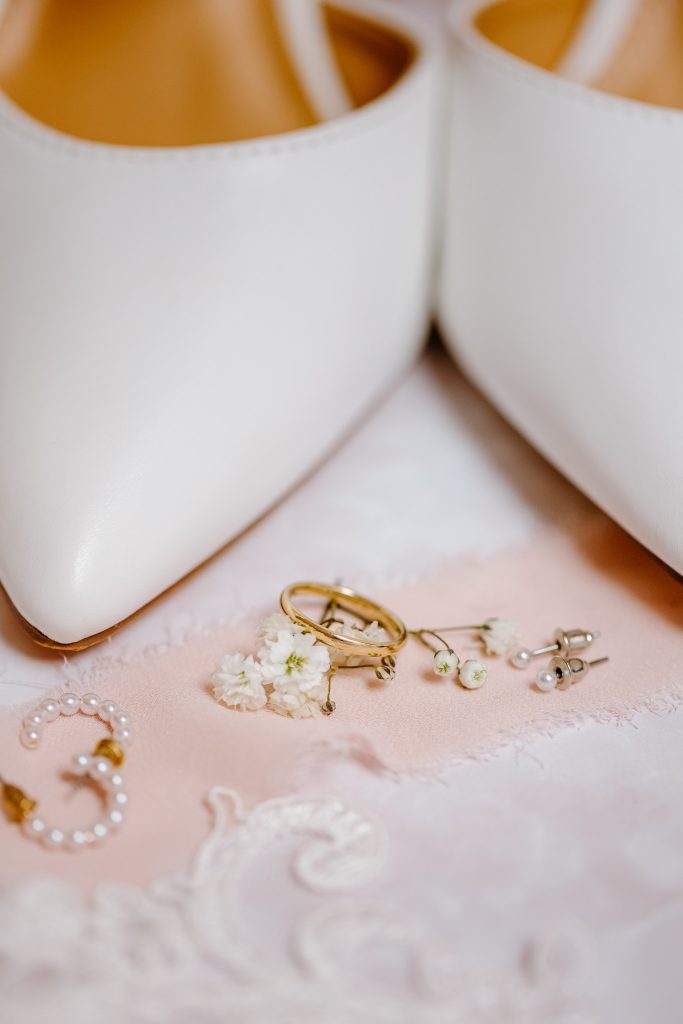 Een paar witte trouwschoenen versierd met parels en een ring, perfect voor een mooie ceremonie in de Schepenzaal van het gemeentehuis van Zwolle.