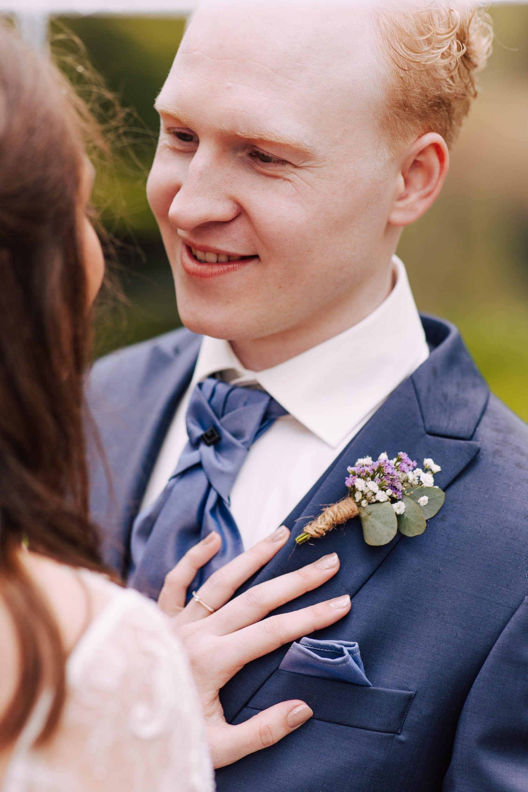 Een man in pak doet een corsages om.