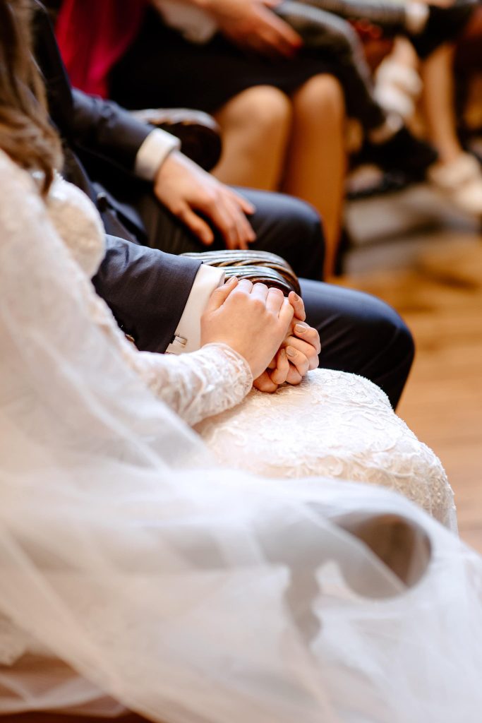 Foto van een bruidspaar hand in hand tijdens hun huwelijksceremonie gemaakt door trouwfotograaf Zwolle.