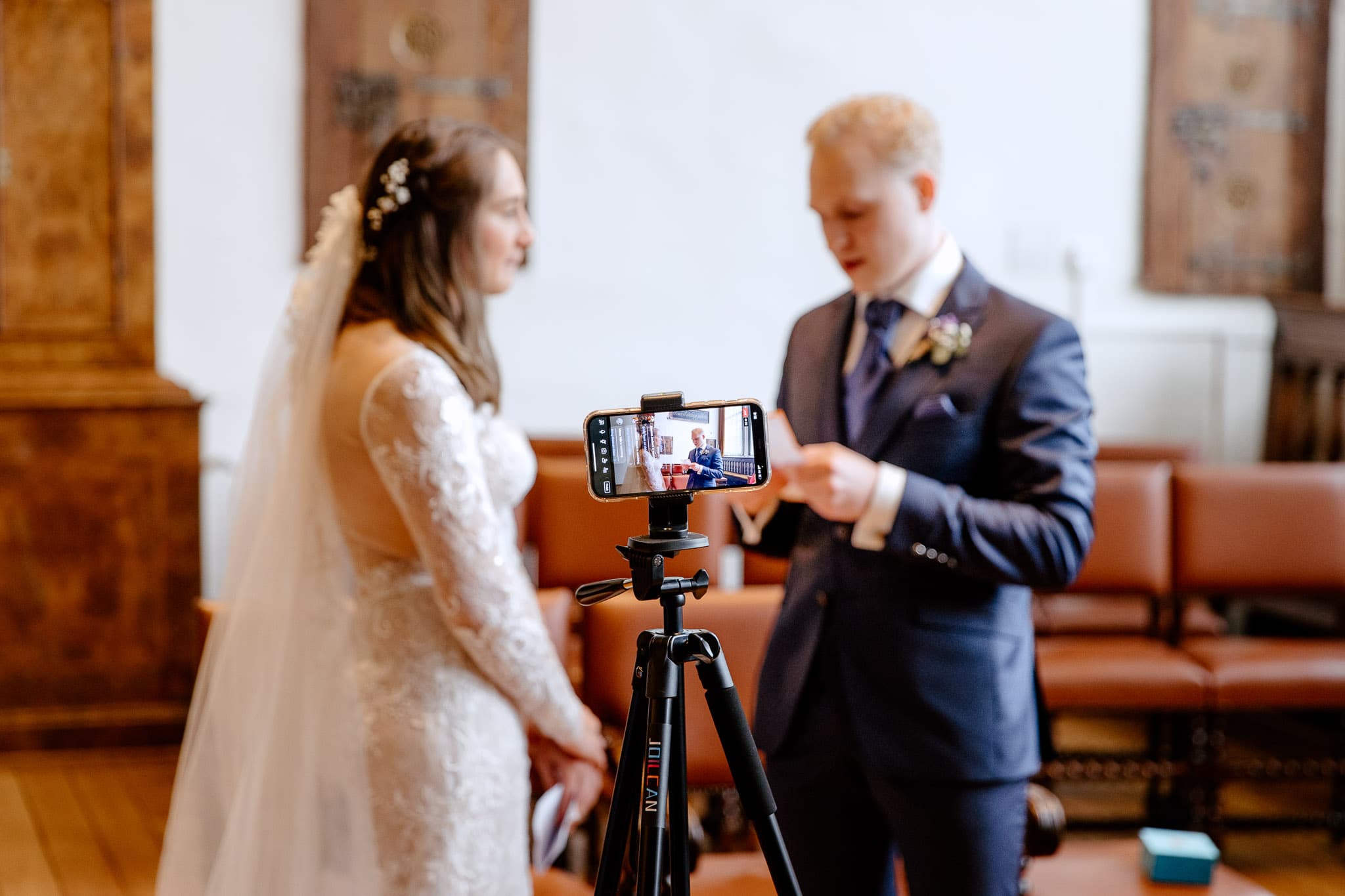 Een bruid en bruidegom die een camera gebruiken voor de livestream van hun huwelijksceremonie.