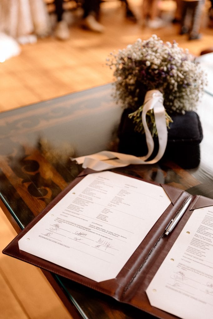 Een huwelijksceremonieboek op een tafel met bloemen erop.