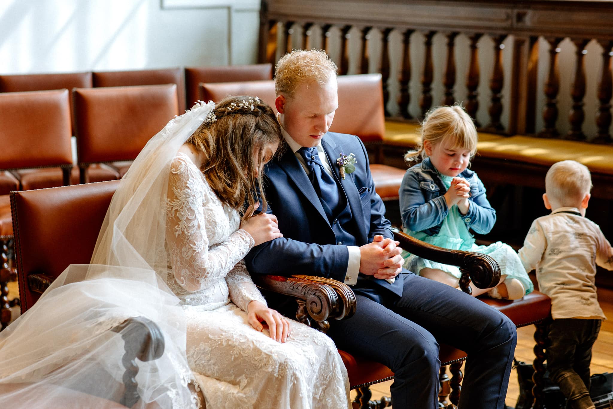 Een bruidspaar en bruidsmeisje bidden tijdens hun trouwceremonie in Zwolle.