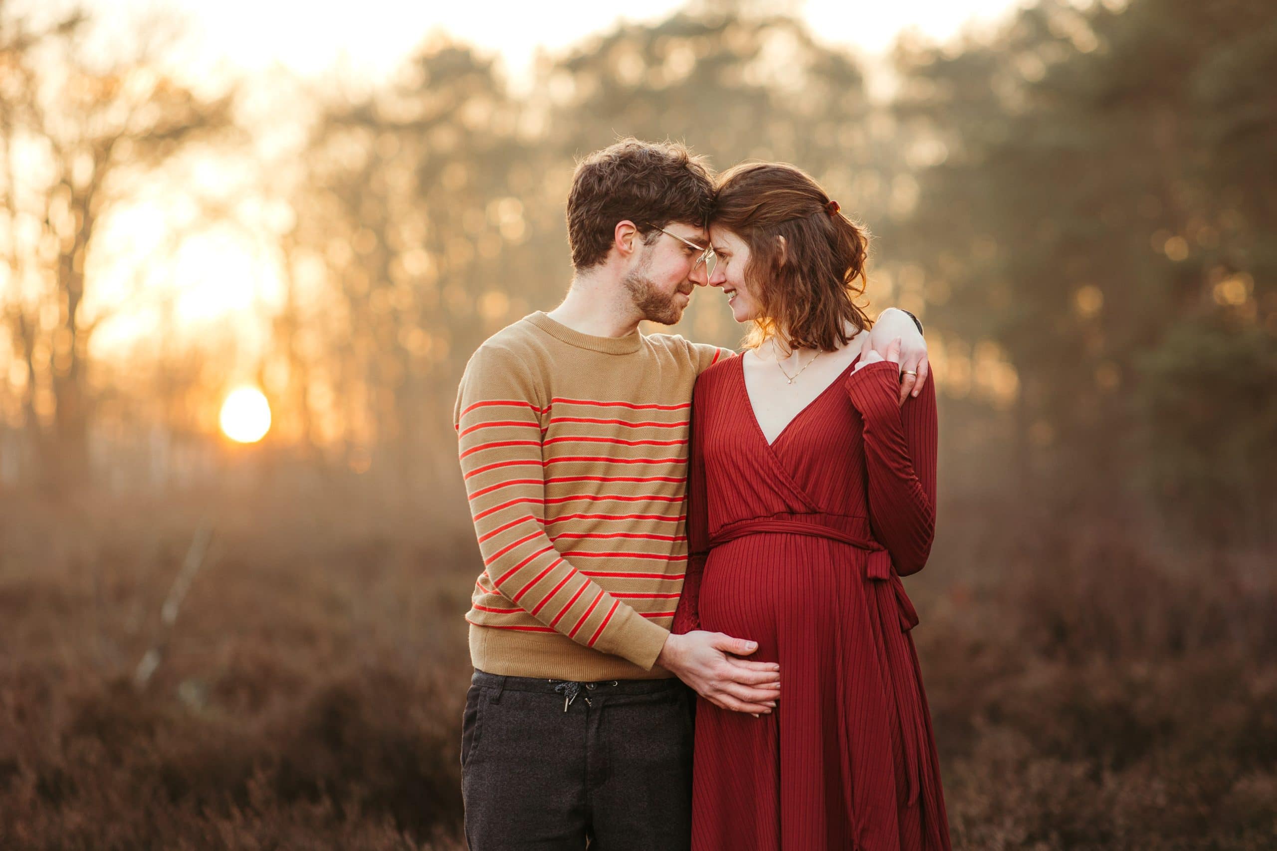 Jonge man en zijn zwangere vrouw kijken elkaar verliefd aan en houden haar beginnende zwangerschapsbuikje vast