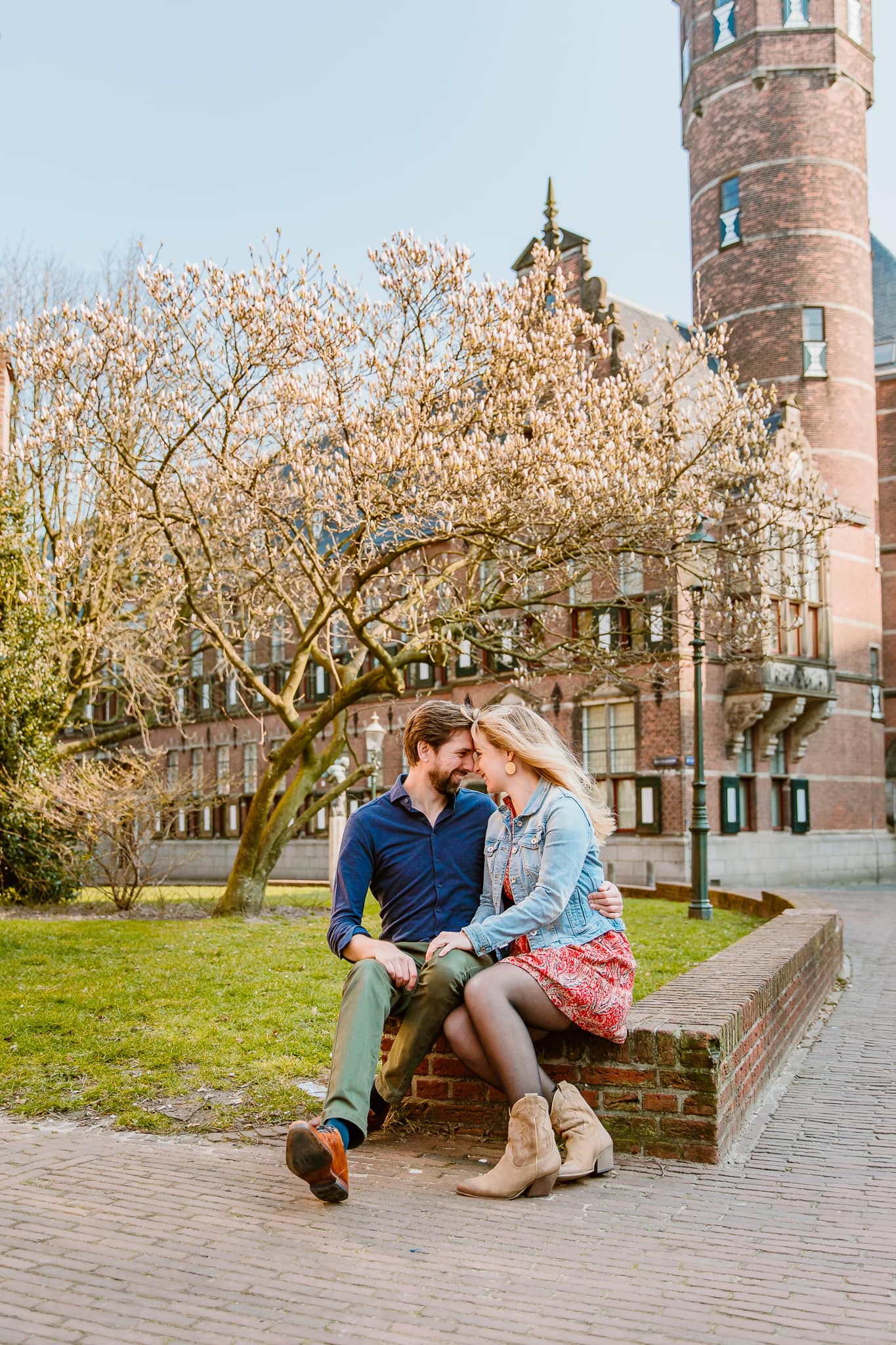 Man en zijn verloofde zitten met hun voorhoofden tegen elkaar onder een bloesemboom bij de Martinikerk in Groningen tijdens een loveshoot.