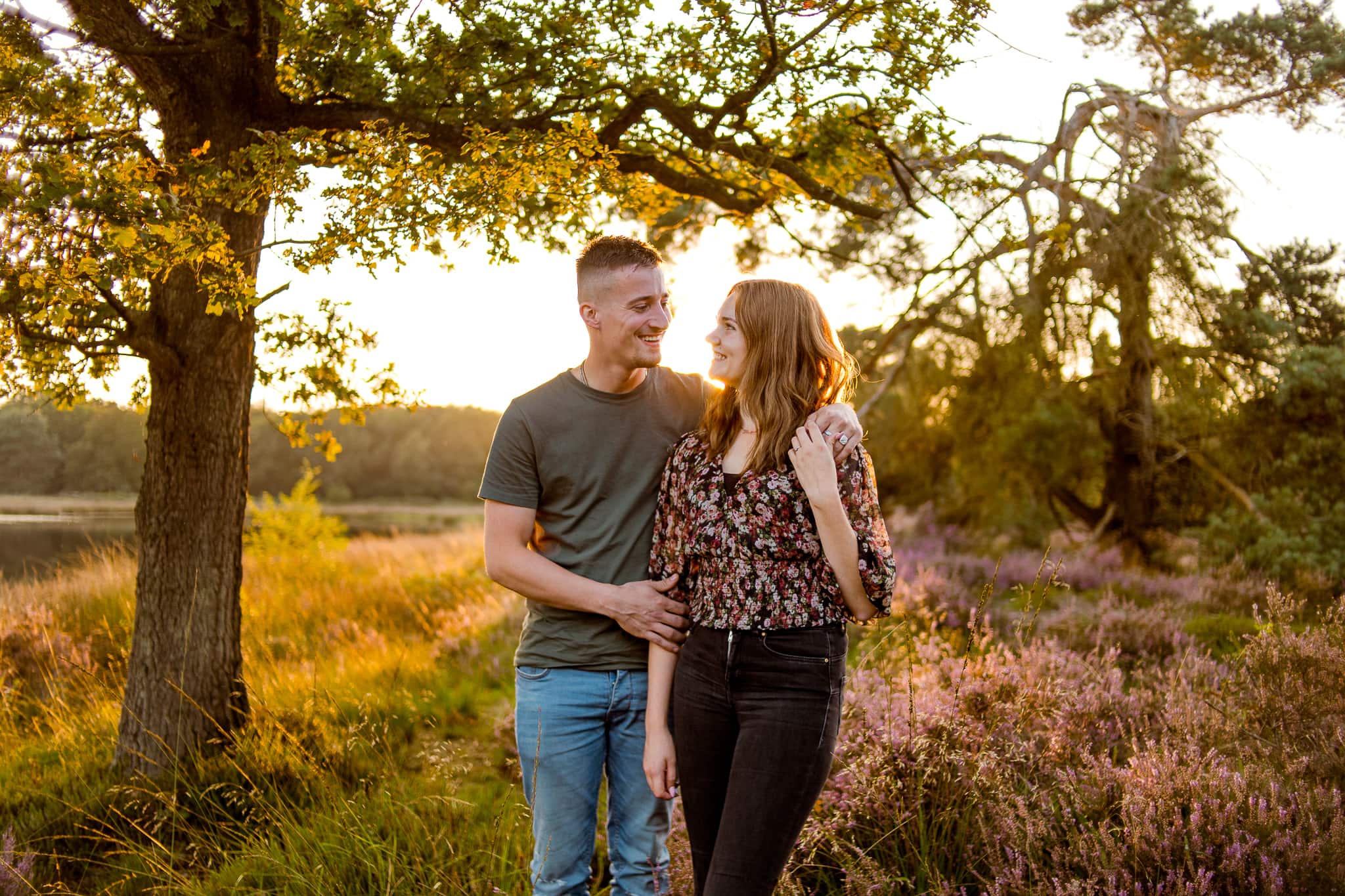 Jongen en meisje staan met armen om elkaar heen in de natuur in Drenthe. Ze kijken elkaar lachend aan.