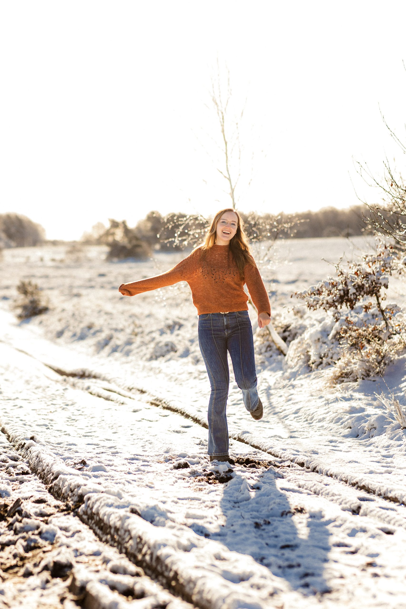 Trouwfotograaf danst lachend in de sneeuw in Drenthe.