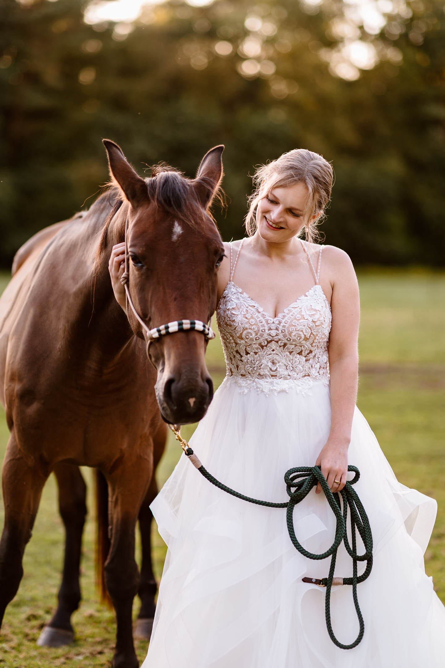 Een vrouw in een witte jurk staat naast een paard.